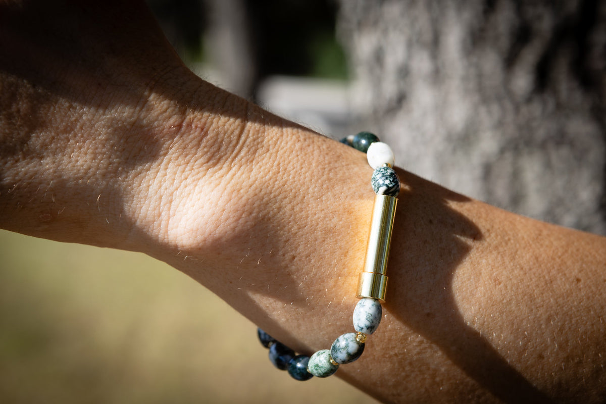 Close-up of a wrist wearing a beaded cremation bracelet with a blurred natural background